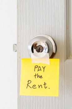 sticky note write a message pay the rent on the latch door