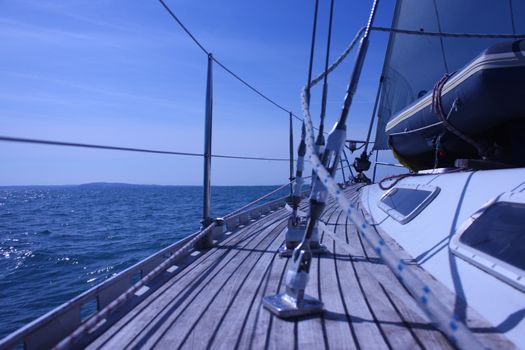 The curved teak deck of a yacht sailing at sea