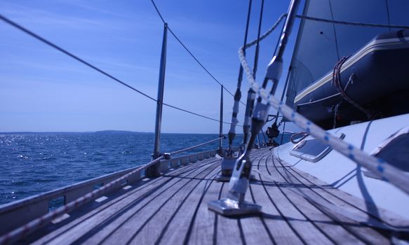 The curved teak deck of a yacht sailing at sea