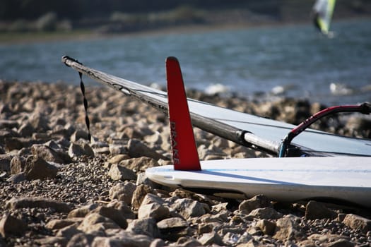 windsurfing board with fin upturned on a beach