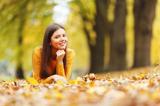 Girl laying on leafs in the autumn park