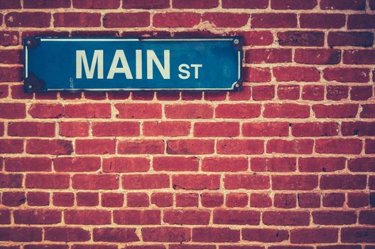 Retro Filtered Photo Of A Main Street Sign On A Red Brick Wall