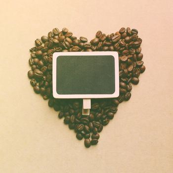 Heart shape from coffee beans with blank blackboard, retro filter effect