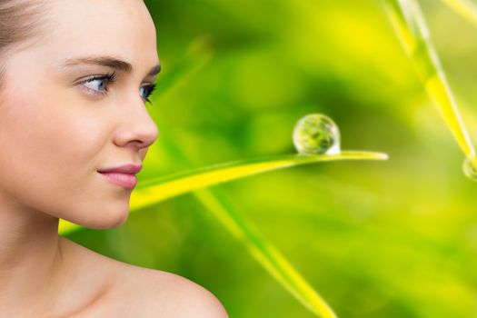 Smiling blonde natural beauty against dew drop on blade of grass