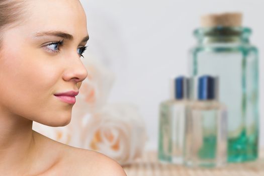 Smiling blonde natural beauty against glass jars and rose flowers in spa