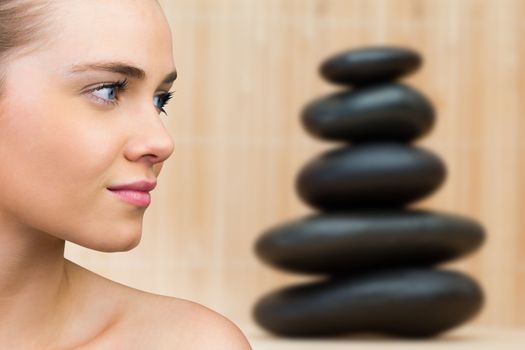Smiling blonde natural beauty against stack of smooth balancing rocks
