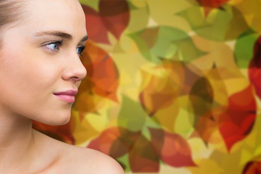 Smiling blonde natural beauty against autumnal leaf pattern in warm tones