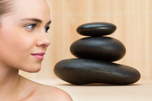 Smiling blonde natural beauty against stack of smooth balancing rocks