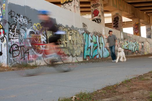 Atlanta, GA, USA - November 2, 2013:  Motion blur of people exercising along a graffiti covered trail that is part of the Atlanta Beltline, a 22-mile long urban redevelopment project for the city of Atlanta. 