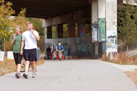 Atlanta, GA, USA - November 2, 2013:  A young couple walks and eats popsicles along a graffiti covered path that is part of the 22-mile Atlanta Beltline urban redevelopment project.  The Beltline will eventually connect 45 intown neighborhoods.