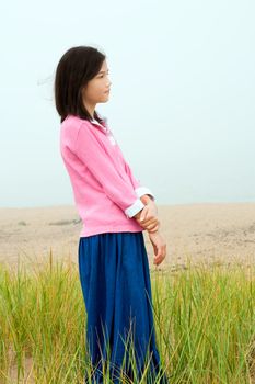 Young biracial girl quietly standing on misty foggy green field
