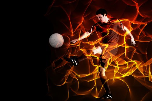 Football player in red kicking against abstract orange glowing black background