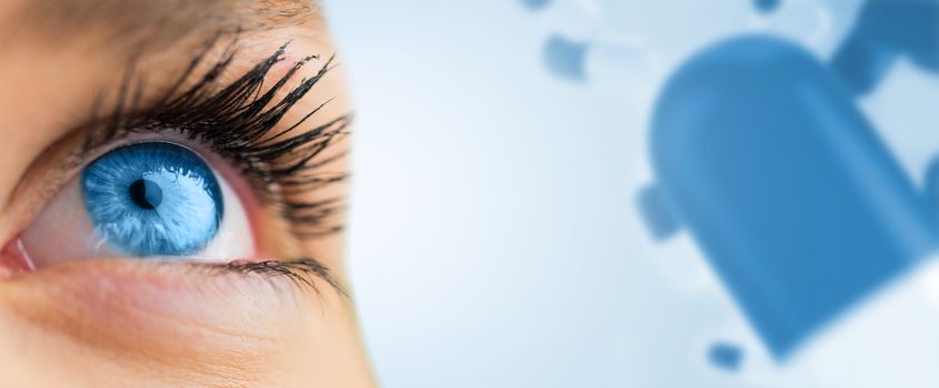 Blue eye looking up on female face against blue medical background with pills