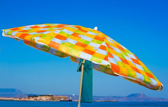 White umbrellas for protection against the sun on a sea beach and the clothes hidden under them.