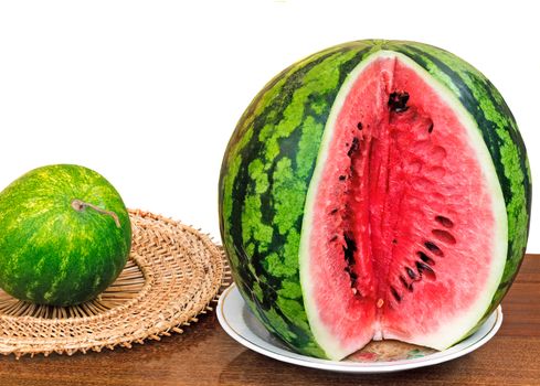 On a table surface on a dish the cut water-melon is located. It is presented on a white background.