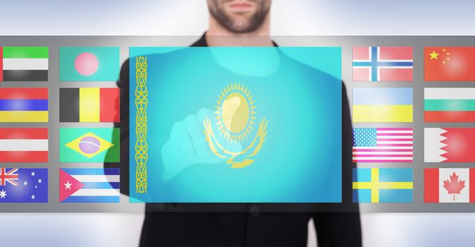 Hand pushing on a touch screen interface, choosing language or country, Kazakhstan