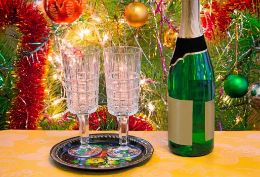 On a table the decorated Christmas fir-tree has wine and two wine glasses for wine.