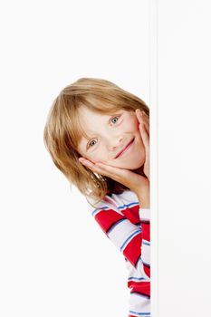 Boy With Blond Hair Peeking Out From Behind A White Board Smiling