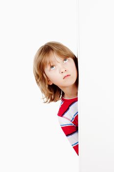 Boy With Blond Hair Peeking Out From Behind A White Board Looking Up