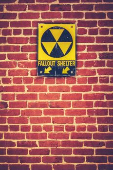 Retro Styled Nuclear Fallout Shelter Sign On A Red brick Wall