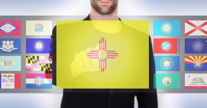 Hand pushing on a touch screen interface, choosing a state, New Mexico