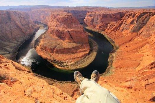 Pair of legs at Horseshoe bend overlook, adventure concept 