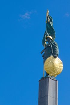 Photo shows details of soldier statue in front of blue sky.