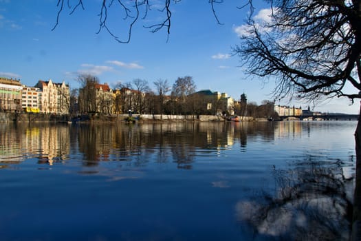 Photo shows various historical houses, Vltava river, bridges and other architectural details.