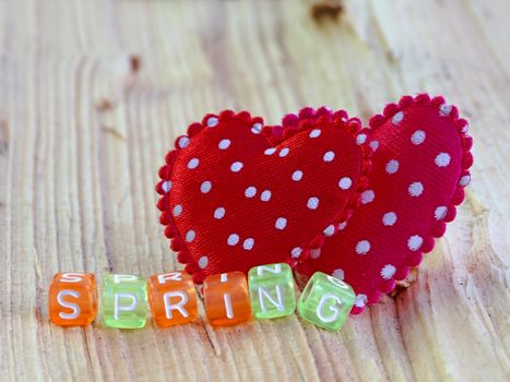 Photo shows details of spring sign with heart on the wooden background.