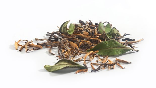 Dried green and yellow tea leaves on the white background