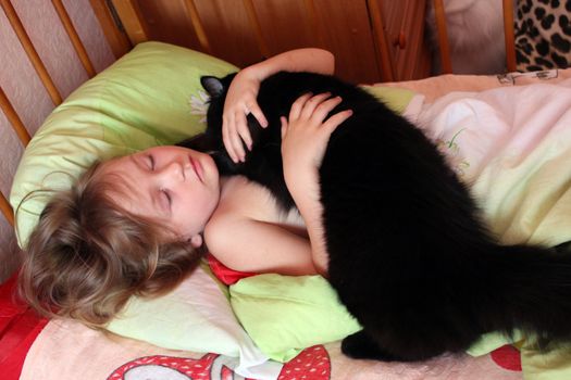 little girl playing with her cat in her bed