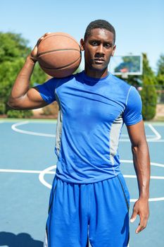 Young basketball player in his early twenties posing on an outdoor court.