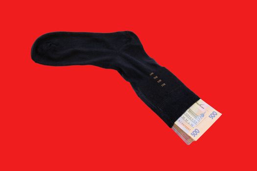 Stack Ukrainian Banknotes five hryvnia in black men's socks on a red background