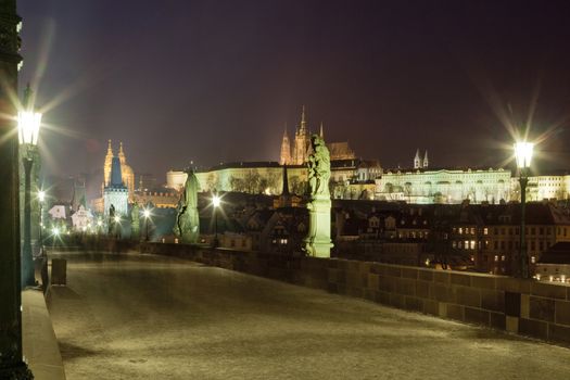 prague in winter - charles bridge and hradcany castle at dusk