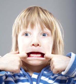 boy with long blond hair making scary faces - isolated on gray