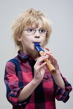 boy with glasses playing his flute - isolated on gray