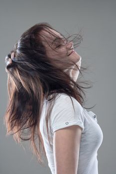 teenage girl with brown hair smiling with her eyes closed - isolated on gray