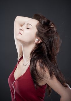 teenage girl listening to music on her personal stereo - isolated on gray