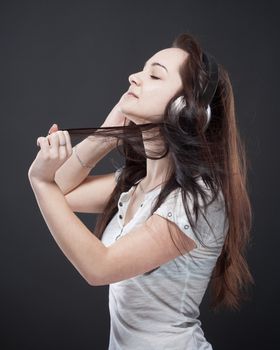 teenage girl with earphones listening to music - isolated on gray