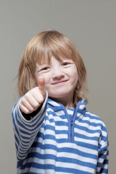 boy with long blond hair showing thumbs up sign, smiling - isolated on gray