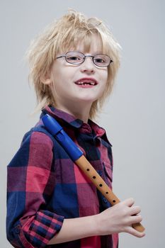 boy with missing milk teeth and glasses holding his flute - isolated on gray