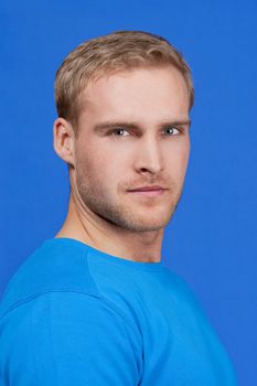 portrait of a young man with blond hair - isolated on blue