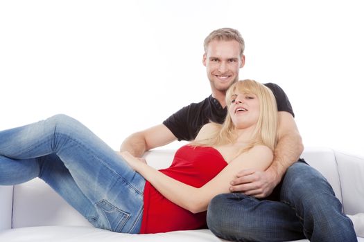 young couple sitting on sofa smiling, embracing