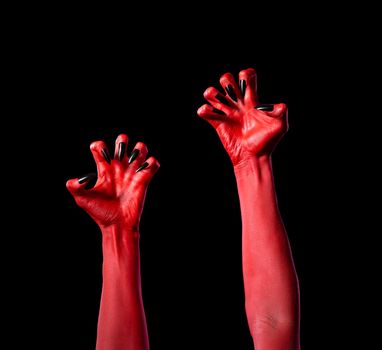 Red devil hands with black nails, Halloween theme, isolated on black background 