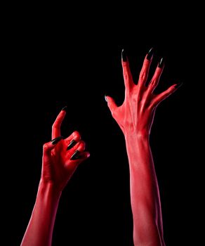 Red spooky devil hands with black nails, Halloween theme, isolated on black background 