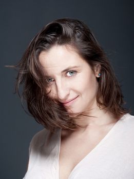 portrait of beautiful woman with brown hair looking - gray background