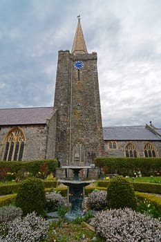 A church steeple and gardens against a stormy sky