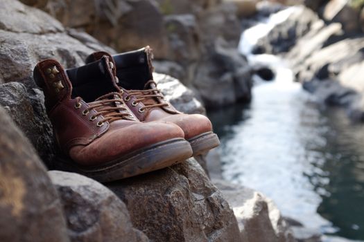 Limited focus hiking boots on rock with blurred river, stream, waterfall at Lotheni. KwaZulu-Natal in the South African Drakensburg mountains