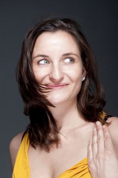 portrait of beautiful woman with brown hair smiling - gray background