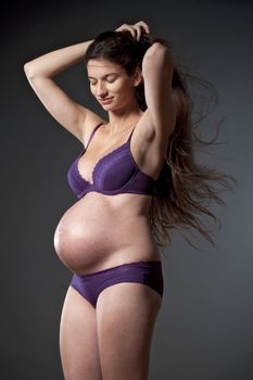 pregnant woman with very long brown hair in purple underwear